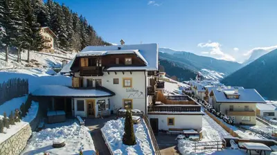 a house on a snowy hill with snow on the ground at Waldheim Appartements in Bressanone