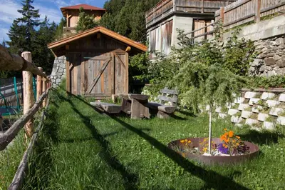 a garden with a wooden gate and a small tree at Waldheim Appartements in Bressanone