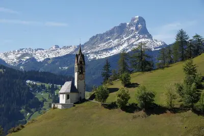 a church on a hill with a mountain in the background at Miribunghof in La Valle