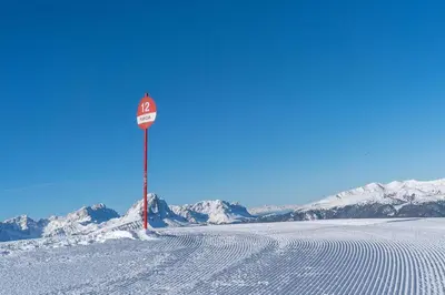 a sign in the snow with mountains in the background at Kronplatz Mountain Lodge in Brunico