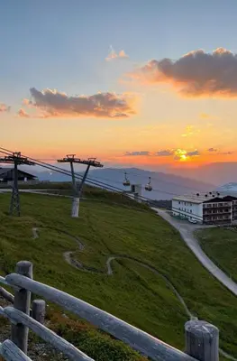 a sunset over a field with a fence at Kronplatz Mountain Lodge in Brunico