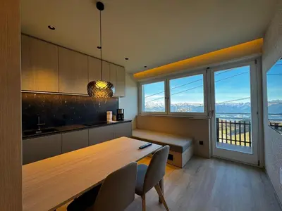 a kitchen with a wooden table and a large window at Kronplatz Mountain Lodge in Brunico