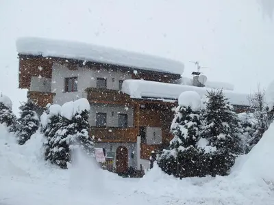 a house covered in snow with trees in front of it at Chalet Belvedere in Arabba