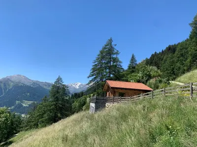 a cabin on a hill with mountains in the background at Chalet Leitn-Anger in San Leonardo in Passiria