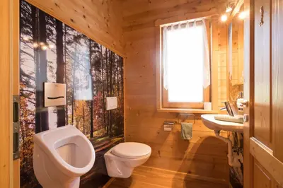 a bathroom with a toilet and a sink and a urinal at Chalet Leitn-Anger in San Leonardo in Passiria