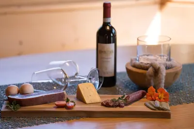 a bottle of wine and a cutting board with meat and cheese at Chalet Leitn-Anger in San Leonardo in Passiria