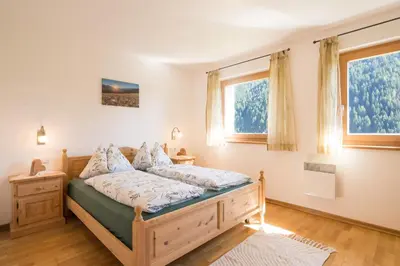 a bedroom with a bed and two windows at Chalet Leitn-Anger in San Leonardo in Passiria