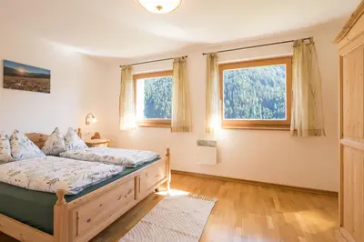 a bedroom with a bed and two windows at Chalet Leitn-Anger in San Leonardo in Passiria