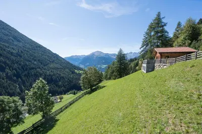a house on top of a grassy hill with mountains at Chalet Leitn-Anger in San Leonardo in Passiria