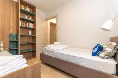 a bedroom with two beds and a book shelf at Casa Carducci in Alleghe
