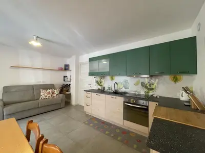 a kitchen with green cabinets and a couch at Casa Carducci in Alleghe