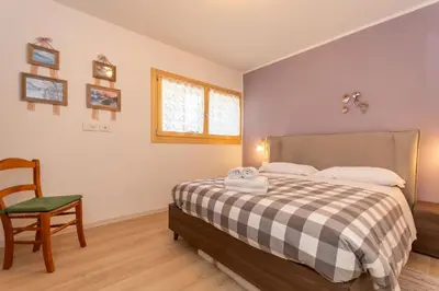 a bedroom with a bed and a chair and a window at Casa Carducci in Alleghe