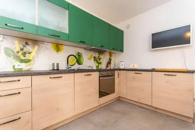 a kitchen with wooden cabinets and a tv on the wall at Casa Carducci in Alleghe