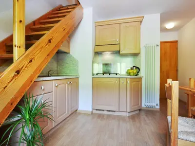 a kitchen with wooden cabinets and a staircase at Apartment Penia 2-1 by Interhome in Penia