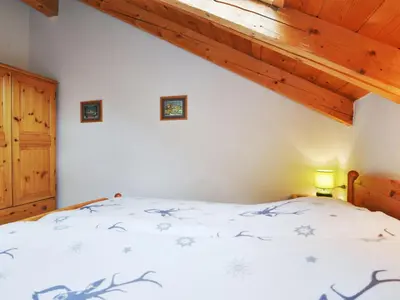 a bedroom with a bed with white sheets and wooden ceilings at Apartment Villa Placidia Apt 34 by Interhome in Campitello di Fassa