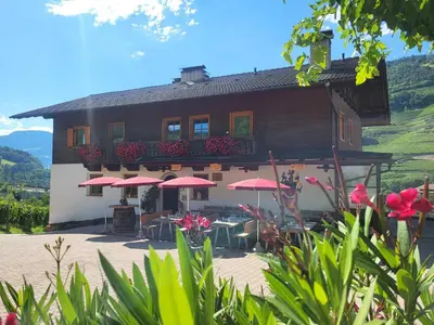 a building with tables and umbrellas in front of it at Martscholer Weinhof in Chiusa