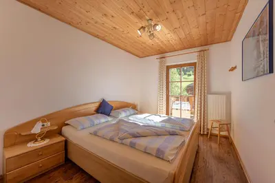 a bedroom with a bed and a wooden ceiling at Schusterhof - Urlaub auf dem Bauernhof in Novale
