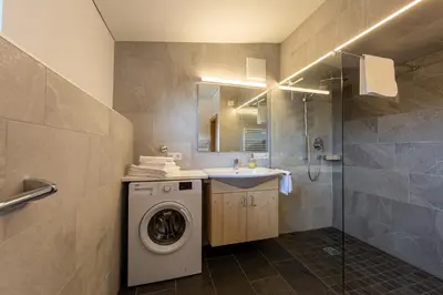 a bathroom with a washing machine and a sink at Schusterhof - Urlaub auf dem Bauernhof in Novale