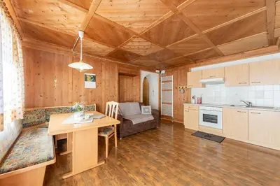 a kitchen and living room with a wooden ceiling at Schusterhof - Urlaub auf dem Bauernhof in Novale