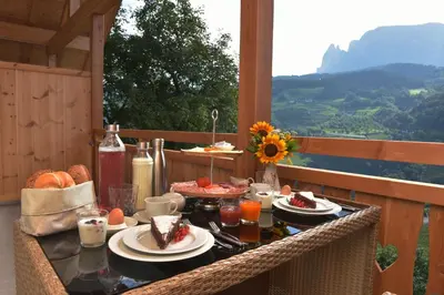 a table with food on a balcony with a view at Pignathof Rosacea in Campodazzo