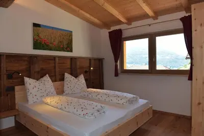 a bedroom with a bed with a wooden headboard and a window at Pignathof Rosacea in Campodazzo