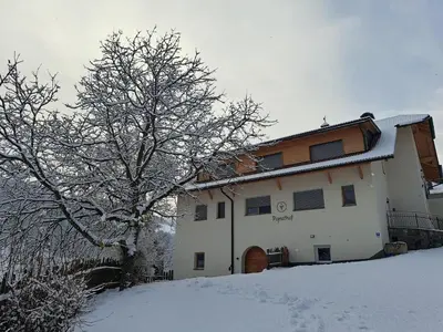 a snow covered building with a tree in front of it at Pignathof Rosacea in Campodazzo