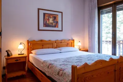 a bedroom with a large wooden bed with two lamps at Appartamenti Des Alpes in Canazei