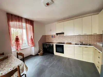 a kitchen with white cabinets and a table and a window at Casa vacanze Da Bianca in Castelfondo