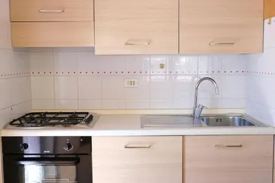 a kitchen with wooden cabinets and a stainless steel sink at Apartments Anny in Canazei