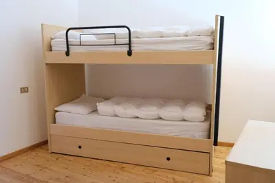 a bunk bed with white sheets and towels at Apartments Anny in Canazei