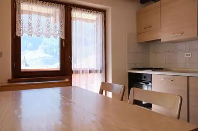 a kitchen with a table and chairs and a window at Apartments Anny in Canazei