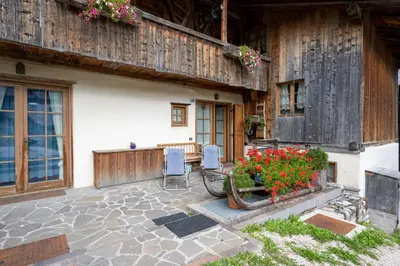 a patio with two chairs and flowers in front of a house at Casa Lacedel 1, on ski slopes in Cortina dʼAmpezzo
