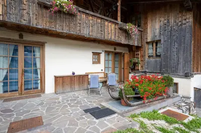 a patio of a house with two chairs and flowers at Casa Lacedel 1, on ski slopes in Cortina dʼAmpezzo