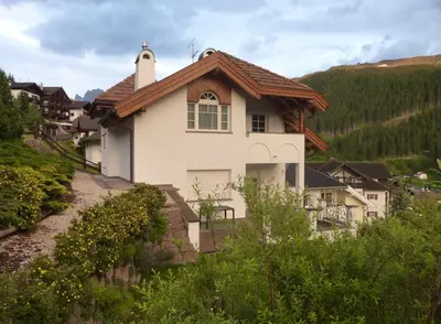a white house on a hill with trees at Appartamenti Valpinoi in Santa Cristina in Val Gardena