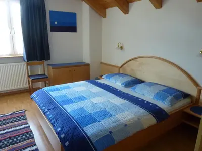 a bedroom with a blue and white bed and a window at Appartamenti Valpinoi in Santa Cristina in Val Gardena