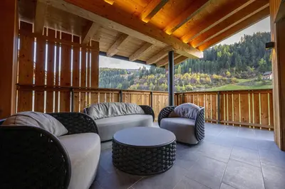 a screened in porch with couches and a table and chairs at Chalet Urela Luxury Apartment in Santa Cristina in Val Gardena