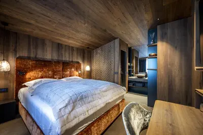 a bedroom with a large bed and a wooden wall at Chalet Urela Luxury Apartment in Santa Cristina in Val Gardena