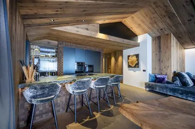 a kitchen with a bar with stools at Chalet Urela Luxury Apartment in Santa Cristina in Val Gardena