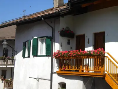 a house with a balcony with flowers on it at B&B fam. Ausermiller in Castello di Fiemme