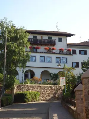 a white building with red flowers on the balconies at Gasthof zum Roessl in San Genesio Atesino