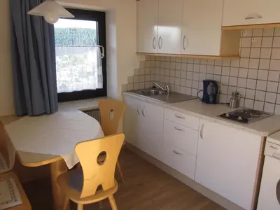 a kitchen with white cabinets and a table and chairs at Gasthof zum Roessl in San Genesio Atesino