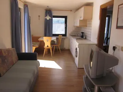 a living room with a couch and a kitchen with a table at Gasthof zum Roessl in San Genesio Atesino