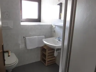 a bathroom with a sink and a toilet and a window at Gasthof zum Roessl in San Genesio Atesino