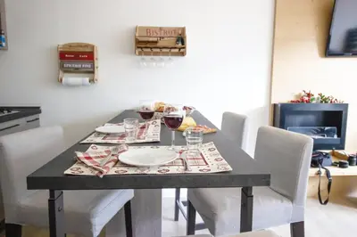 a dining table with white chairs and wine glasses at Casa Franz in Val di Fassa by Zoom In Earth in Mazzin