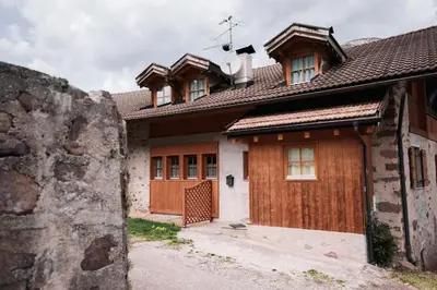 a house with wooden doors and a wall at Zirmo - Your nordic stay in Tesero
