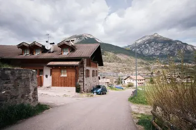 a house on a road with mountains in the background at Zirmo - Your nordic stay in Tesero