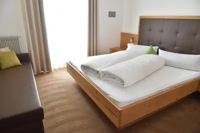 a bed with white sheets and pillows in a room at Pension Gasthof Haselstaude in San Leonardo in Passiria