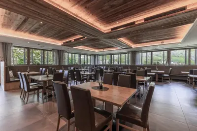 a dining room with tables and chairs and windows at Pension Gasthof Haselstaude in San Leonardo in Passiria