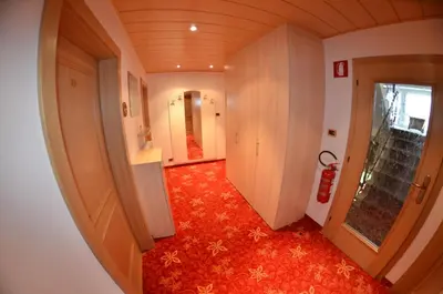 a hallway with a red carpeted floor and a room with a door at Garni Ossi in Santa Cristina in Val Gardena