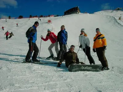 a group of people standing in the snow with a snowboard at Garni Ossi in Santa Cristina in Val Gardena